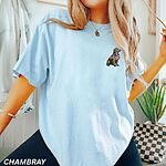 Woman in a loose Chambray T-shirt with a sitting golden retriever draped in an American flag on the left chest