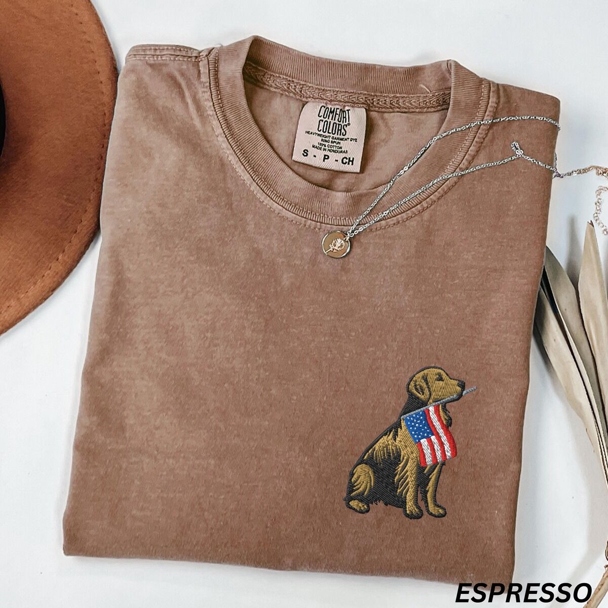 Golden Retriever American Flag Shirt – Espresso Espresso T-shirt folded with a necklace, a golden retriever with a stars-and-stripes flag stitched on the left chest