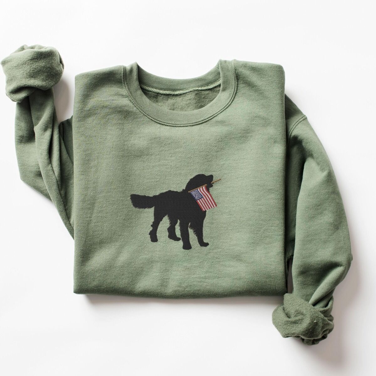 Golden Retriever American Flag Sweatshirt – Military Green Military Green crewneck sweatshirt laid flat, a black golden retriever holding a stars-and-stripes flag stitched across the chest