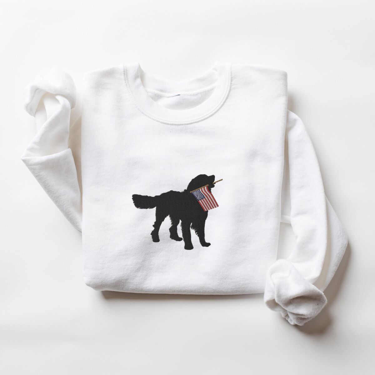 Golden Retriever American Flag Sweatshirt - White White crewneck sweatshirt laid flat, embroidered with a black golden retriever carrying a red, white and blue flag