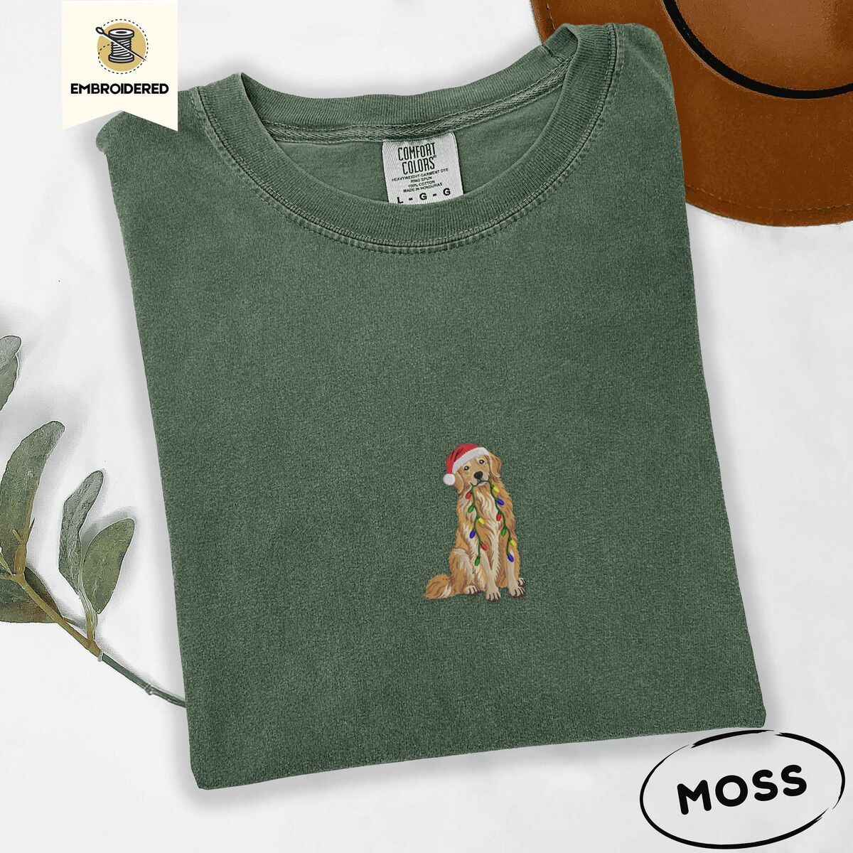 Golden Retriever Christmas Lights Shirt – Moss Moss Comfort Colors T-shirt embroidered with a golden retriever in a red Santa hat holding a strand of colorful Christmas lights