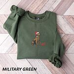 Military Green crewneck sweatshirt laid flat on a wood floor, embroidered with a golden retriever in a Santa hat beside a gift box