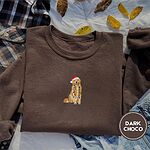 Dark Chocolate crewneck sweatshirt on a plaid flannel shirt with yellow autumn leaves and denim shorts, embroidered with a golden retriever in a Santa hat holding Christmas lights in the center of the chest