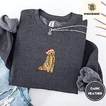 Dark Heather crewneck sweatshirt folded with ripped jeans and a silver chain necklace, embroidered with a golden retriever in a Santa hat holding Christmas lights in the center of the chest
