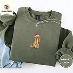 Military Green crewneck sweatshirt folded with light jeans and a silver chain necklace, embroidered with a golden retriever in a Santa hat holding Christmas lights in the center of the chest