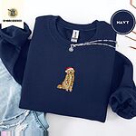 Navy crewneck sweatshirt folded with ripped jeans and a silver chain necklace, embroidered with a golden retriever in a Santa hat holding Christmas lights in the center of the chest