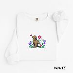 White crewneck sweatshirt laid flat, embroidered with a sitting golden retriever among spring flowers and a pink butterfly
