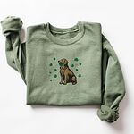 Military Green crewneck sweatshirt laid flat, embroidered with a sitting golden retriever holding a four leaf clover in its mouth, ringed by green shamrocks