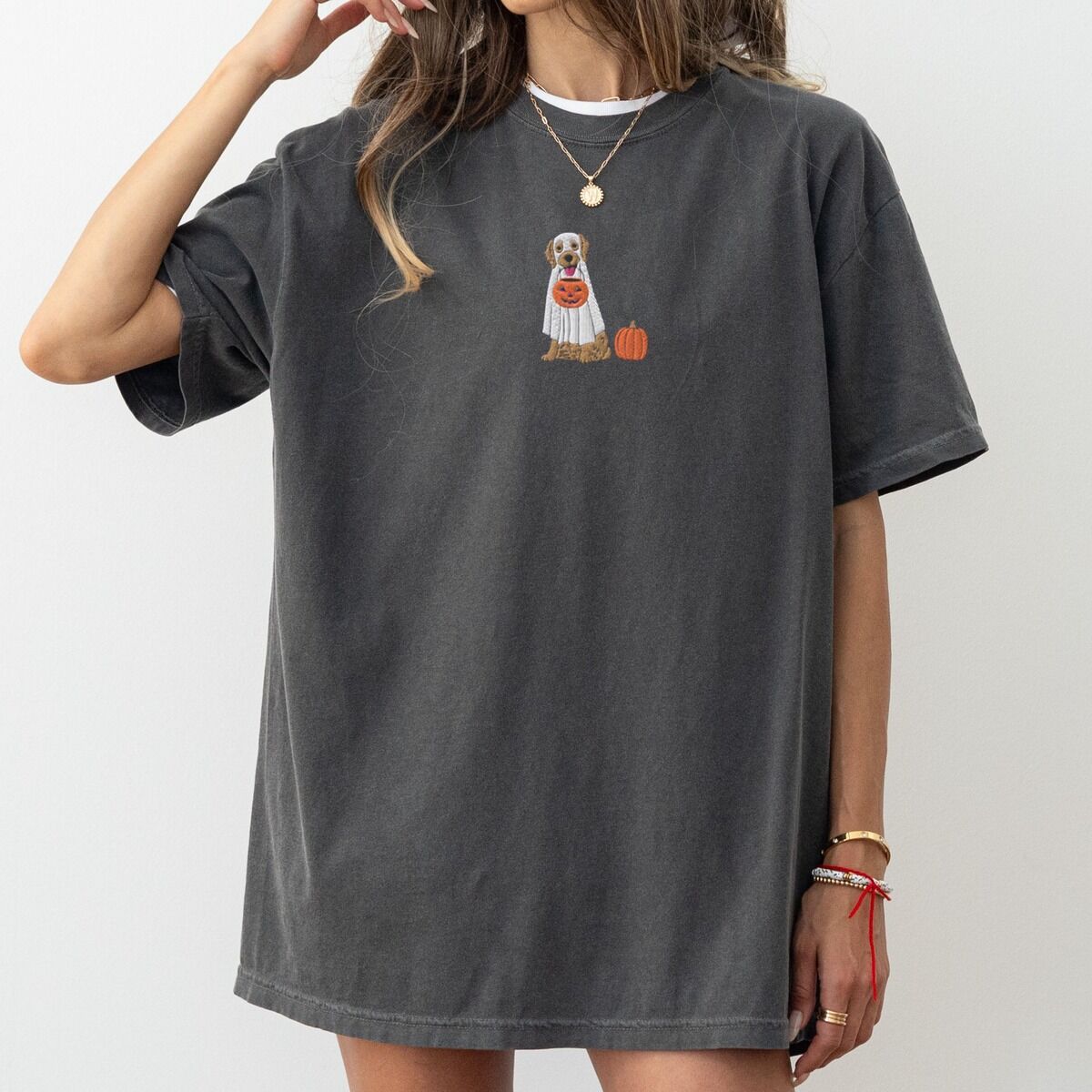 Golden Retriever Ghost Shirt – Pepper Woman in an oversized Pepper T-shirt embroidered with a golden retriever in a white ghost sheet carrying a jack-o'-lantern trick-or-treat bucket beside a small pumpkin