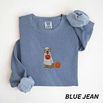 Blue Jean crewneck sweatshirt folded flat with a rolled cuff, embroidered with a golden retriever in a white ghost sheet carrying a jack-o'-lantern trick-or-treat bucket beside a small pumpkin