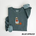 Blue Spruce crewneck sweatshirt folded flat with a rolled cuff, embroidered with a golden retriever in a white ghost sheet carrying a jack-o'-lantern trick-or-treat bucket beside a small pumpkin