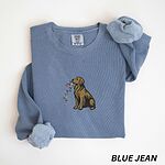 Blue Jean crewneck sweatshirt laid flat, embroidered with a sitting golden retriever holding a strand of Christmas lights