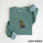 Golden retriever holding Christmas lights sweatshirt in Light Green laid flat with rolled cuffs, embroidered with a sitting golden carrying a strand of colored bulbs