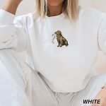 Woman sitting in a White crewneck sweatshirt embroidered with a golden retriever carrying colored Christmas lights in its mouth