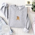 Ash crewneck sweatshirt folded with denim shorts, white sneakers and a potted plant, embroidered with a happy golden retriever lying down with its head up and tongue out