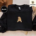 Black crewneck sweatshirt with a brown felt hat and dried bunny tail grass, embroidered with a happy golden retriever lying down with its head up and tongue out