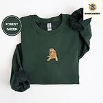 Forest Green crewneck sweatshirt folded on a white background, embroidered with a happy golden retriever lying down with its head up and tongue out