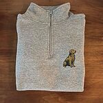 Folded heather grey quarter zip with the zipper up, on a wooden table, embroidered with a small sitting golden retriever on the left chest