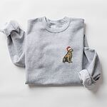 Sport Grey crewneck sweatshirt laid flat, embroidered with a small golden retriever sitting in a red Santa hat on the left chest