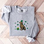 Sport Grey crewneck sweatshirt laid flat on a wood floor, embroidered with a sitting golden retriever in a green leprechaun hat with a pot of gold and green shamrocks