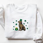 White crewneck sweatshirt laid flat, embroidered with a sitting golden retriever in a green leprechaun hat with a pot of gold and green shamrocks