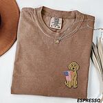 Espresso T-shirt folded with a necklace, a golden doodle holding a small American flag on the left chest