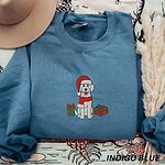 Indigo Blue crewneck sweatshirt beside a tan hat and pampas grass, embroidered with a cream doodle in a Santa hat between two gifts