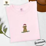 Blossom Comfort Colors T-shirt embroidered with a curly apricot goldendoodle puppy in a Santa hat chewing on a tangled string of Christmas lights