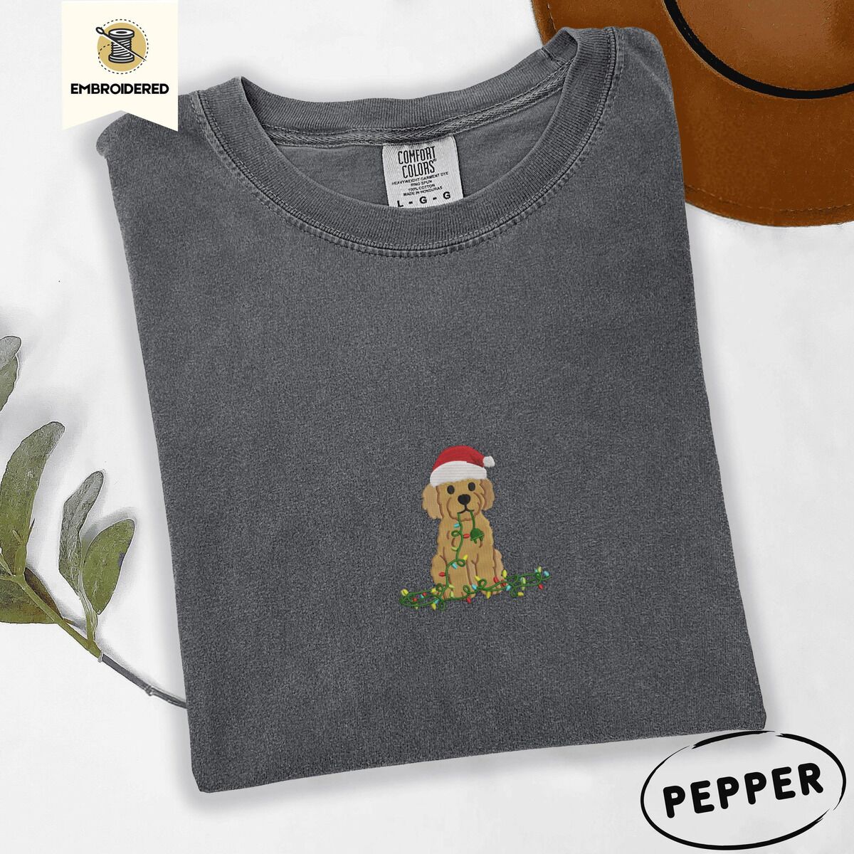 Goldendoodle Christmas Shirt – Pepper Pepper Comfort Colors T-shirt embroidered with a curly apricot goldendoodle puppy in a Santa hat chewing on a tangled string of Christmas lights