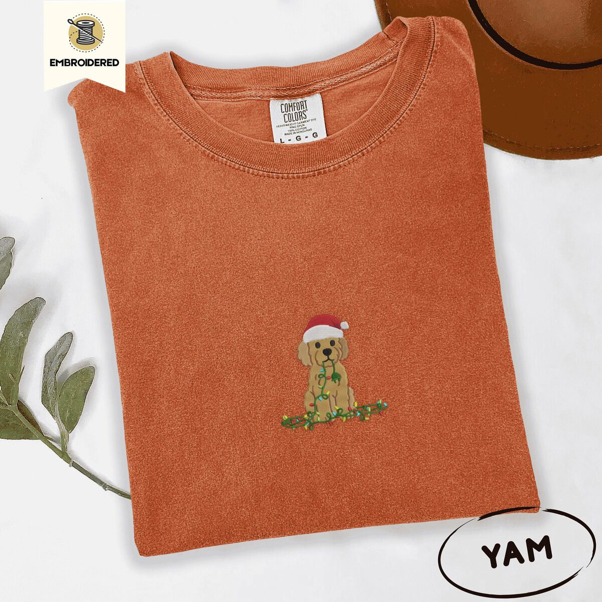 Goldendoodle Christmas Shirt – Yam Yam Comfort Colors T-shirt embroidered with a curly apricot goldendoodle puppy in a Santa hat chewing on a tangled string of Christmas lights