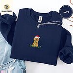 Navy crewneck sweatshirt folded with ripped jeans and a silver chain necklace, embroidered with a goldendoodle puppy in a Santa hat chewing on a tangled string of Christmas lights