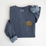 Denim crewneck sweatshirt laid flat with a rolled cuff, embroidered with a small shaggy golden doodle face on the left chest