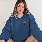 Smiling woman in an Indigo Blue crewneck sweatshirt embroidered with a small golden doodle face on the left chest