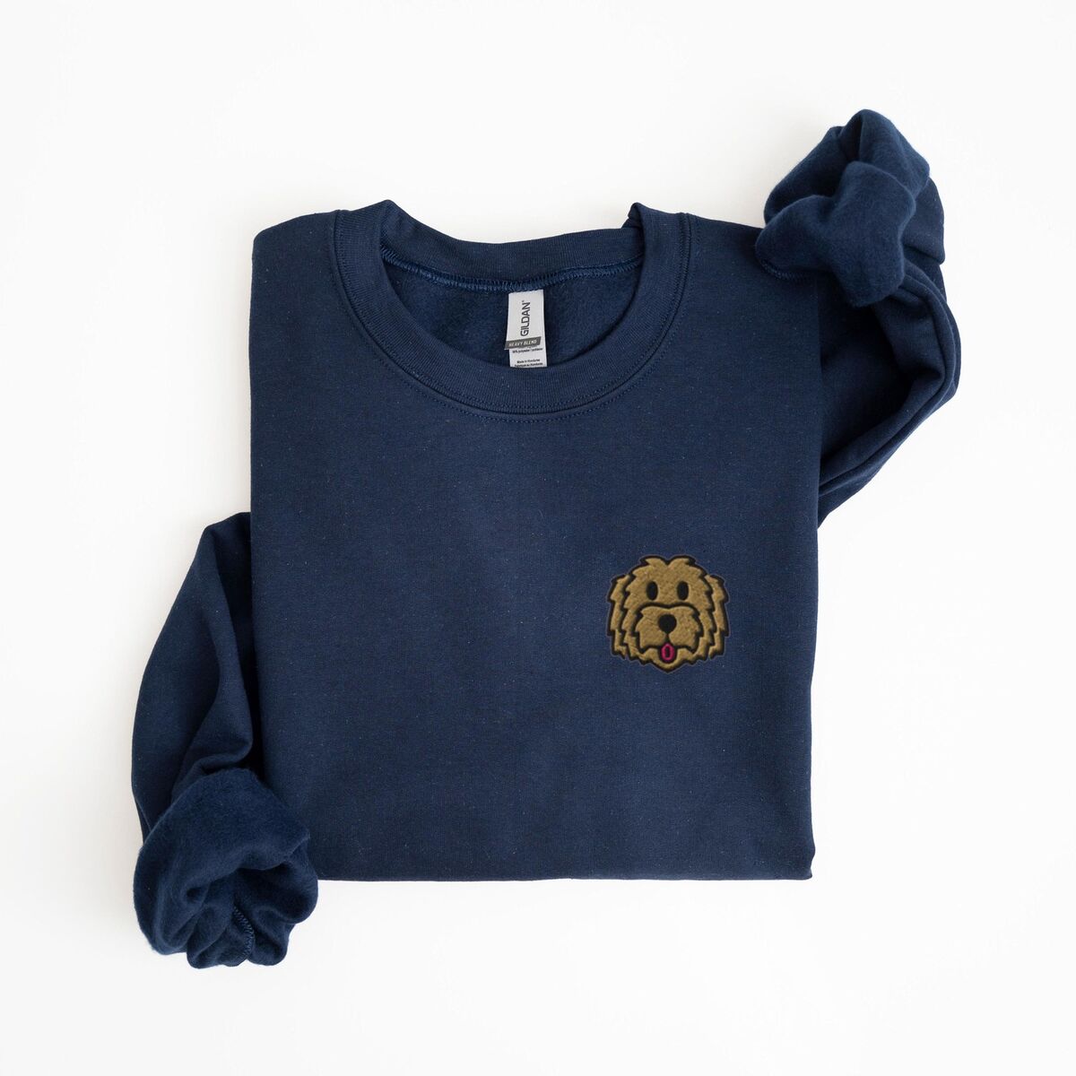 Goldendoodle Face Sweatshirt - Navy Navy crewneck sweatshirt laid flat with a rolled sleeve, embroidered with a small shaggy golden doodle face on the left chest