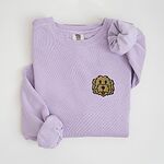 Orchid crewneck sweatshirt laid flat with a knotted sleeve, embroidered with a small shaggy golden doodle face on the left chest