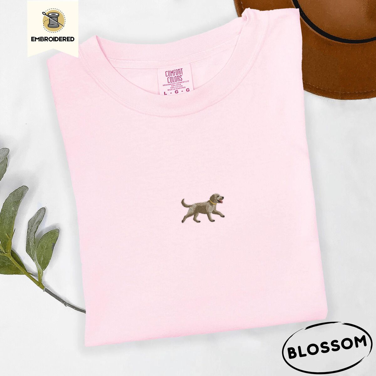 Goldendoodle T-Shirt – Blossom Blossom Comfort Colors T-shirt embroidered with a mini apricot goldendoodle trotting in a gold collar with its tongue out, in the center of the chest