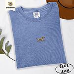 Blue Jean Comfort Colors T-shirt embroidered with a mini apricot goldendoodle trotting in a gold collar with its tongue out, in the center of the chest