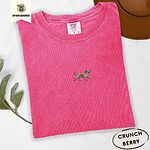 Crunchberry Comfort Colors T-shirt embroidered with a mini apricot goldendoodle trotting in a gold collar with its tongue out, in the center of the chest