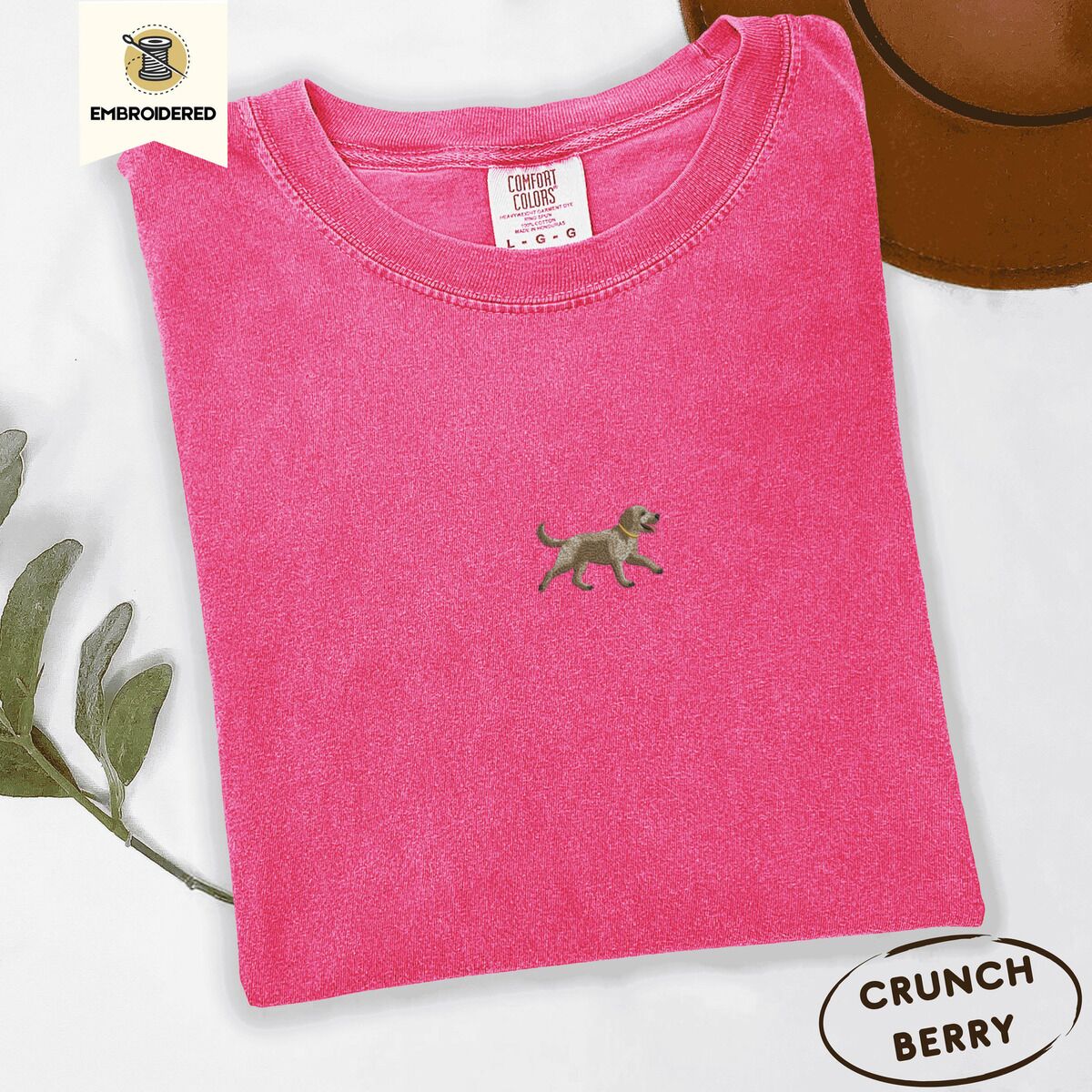 Goldendoodle T-Shirt – Crunchberry Crunchberry Comfort Colors T-shirt embroidered with a mini apricot goldendoodle trotting in a gold collar with its tongue out, in the center of the chest