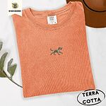 Terracotta Comfort Colors T-shirt embroidered with a mini apricot goldendoodle trotting in a gold collar with its tongue out, in the center of the chest