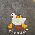 Real Dark Heather grandma duck sweatshirt with four yellow ducklings, two on the mama duck's back and two at her feet, above the word grandma in white thread