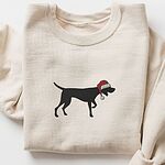 Sand crewneck sweatshirt laid flat on a white background, embroidered with a black German shorthaired pointer silhouette in a red Santa hat