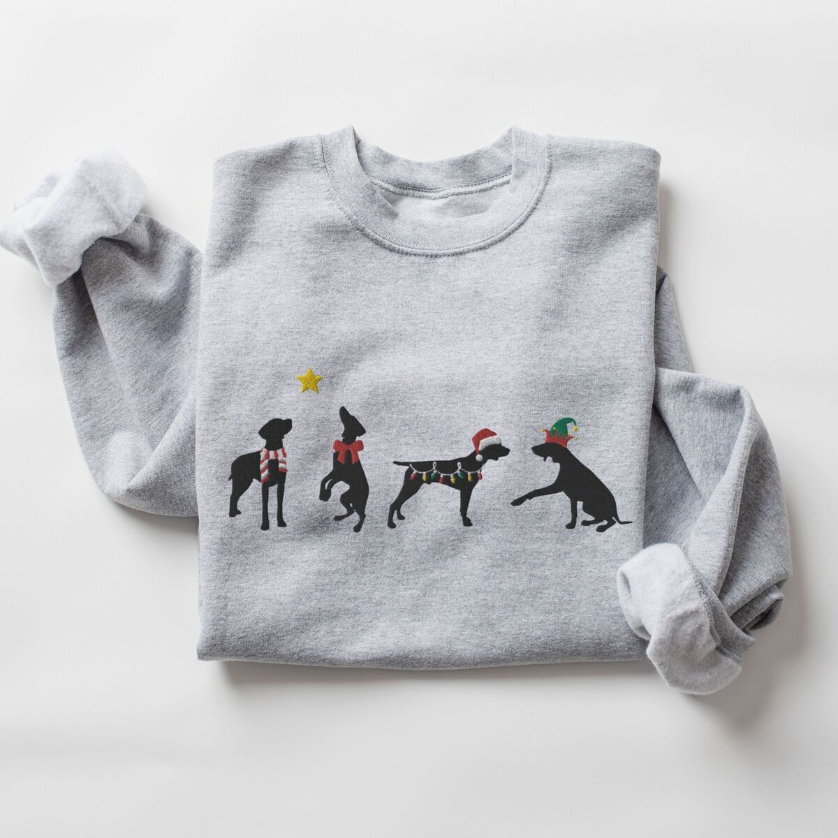 GSP Silhouette Christmas Sweatshirt - Sport Grey Sport Grey crewneck sweatshirt laid flat on a white background, embroidered with four black German shorthaired pointer silhouettes in a striped scarf, a red bow, Christmas lights, a Santa hat and an elf hat under a gold star