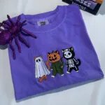 Folded violet Halloween cat shirt with three embroidered costume cats