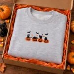 Halloween crewneck folded in a gift box with orange tissue paper and mini pumpkins