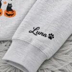 Optional sleeve embroidery with the name Luna and a paw print icon on the Halloween crewneck
