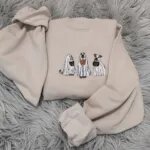 Sand Halloween crewneck with three trick-or-treating ghost dogs embroidered across the chest, sleeves spread out
