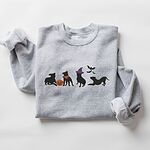 Sport Grey crewneck sweatshirt laid flat on a white background, embroidered with four black pit bull silhouettes with a jack-o'-lantern, an orange bandana, a purple witch hat and bats