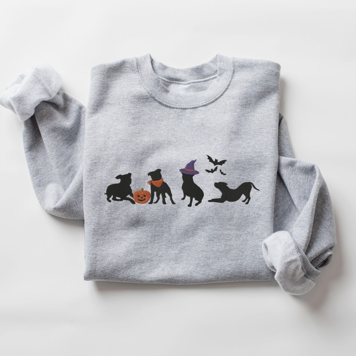 Halloween Pitbull Sweatshirt - Sport Grey Sport Grey crewneck sweatshirt laid flat on a white background, embroidered with four black pit bull silhouettes with a jack-o'-lantern, an orange bandana, a purple witch hat and bats