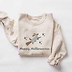 Sand crewneck sweatshirt laid flat on white, embroidered with a dachshund in a ghost sheet riding a broom among stars above the words Happy Halloweenie in black script